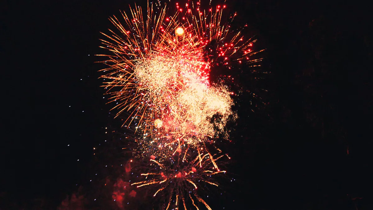 Fireworks bursting red and gold over the night sky.
