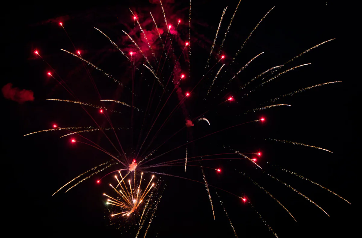 A red and gold firework with falling sparks.