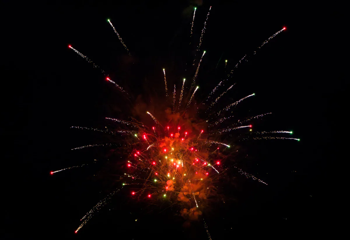 A red and orange burst with long gold trails.