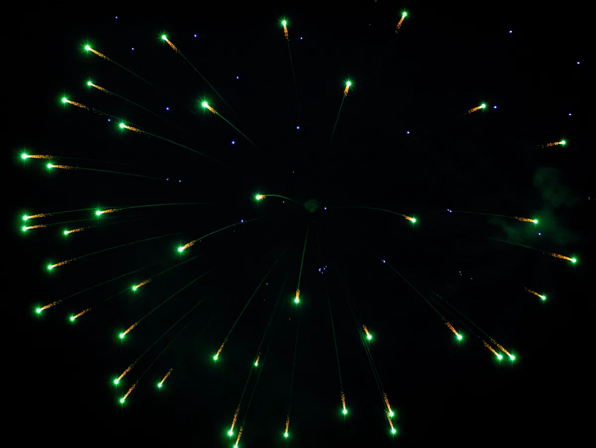 A wide green firework with gold dots.