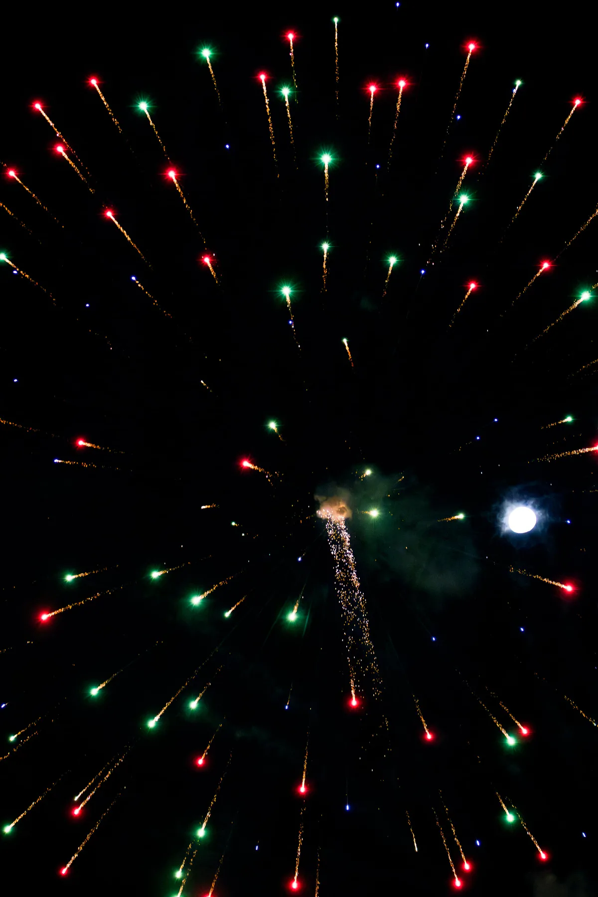 A column of green and red sparks rising in the dark.