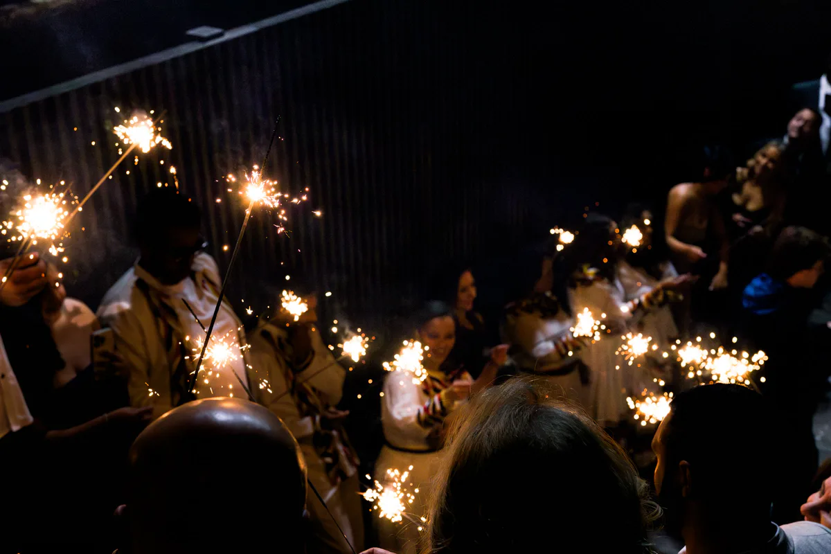 Wedding guests hold up sparklers in the dark.