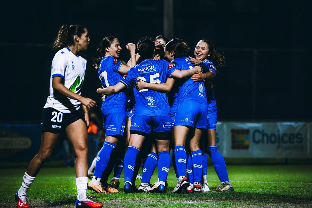 Box Hill United players celebrate together, a player in white beside them.