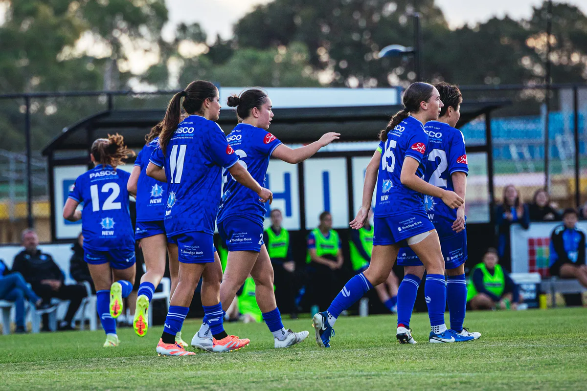 Box Hill United players in blue walk off together past the Box Hill sign.
