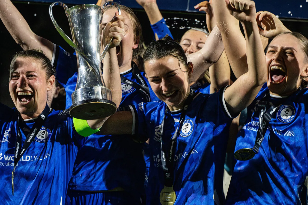 Box Hill United's senior women lift the NPL Victoria trophy on grand final night, shouting, medals round their necks.