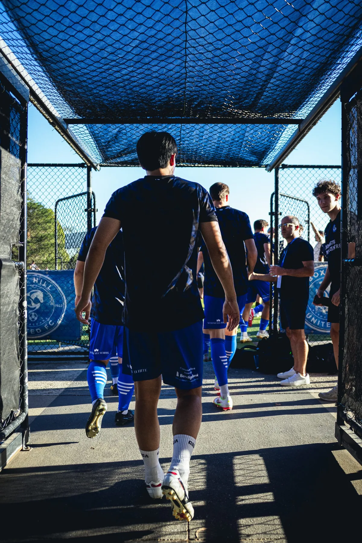 Players walking out through the caged tunnel to the pitch
