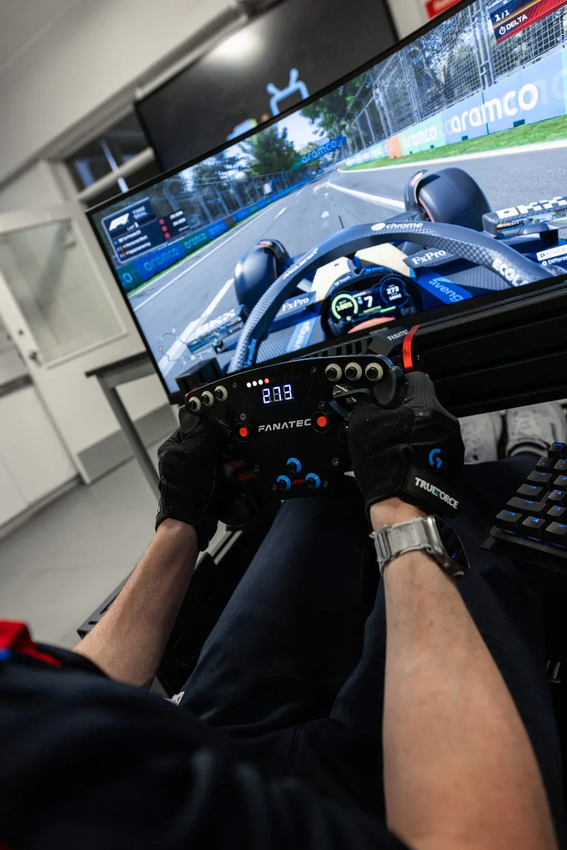 Gloved hands on a sim racing wheel, a Formula 1 race on the ultrawide screen