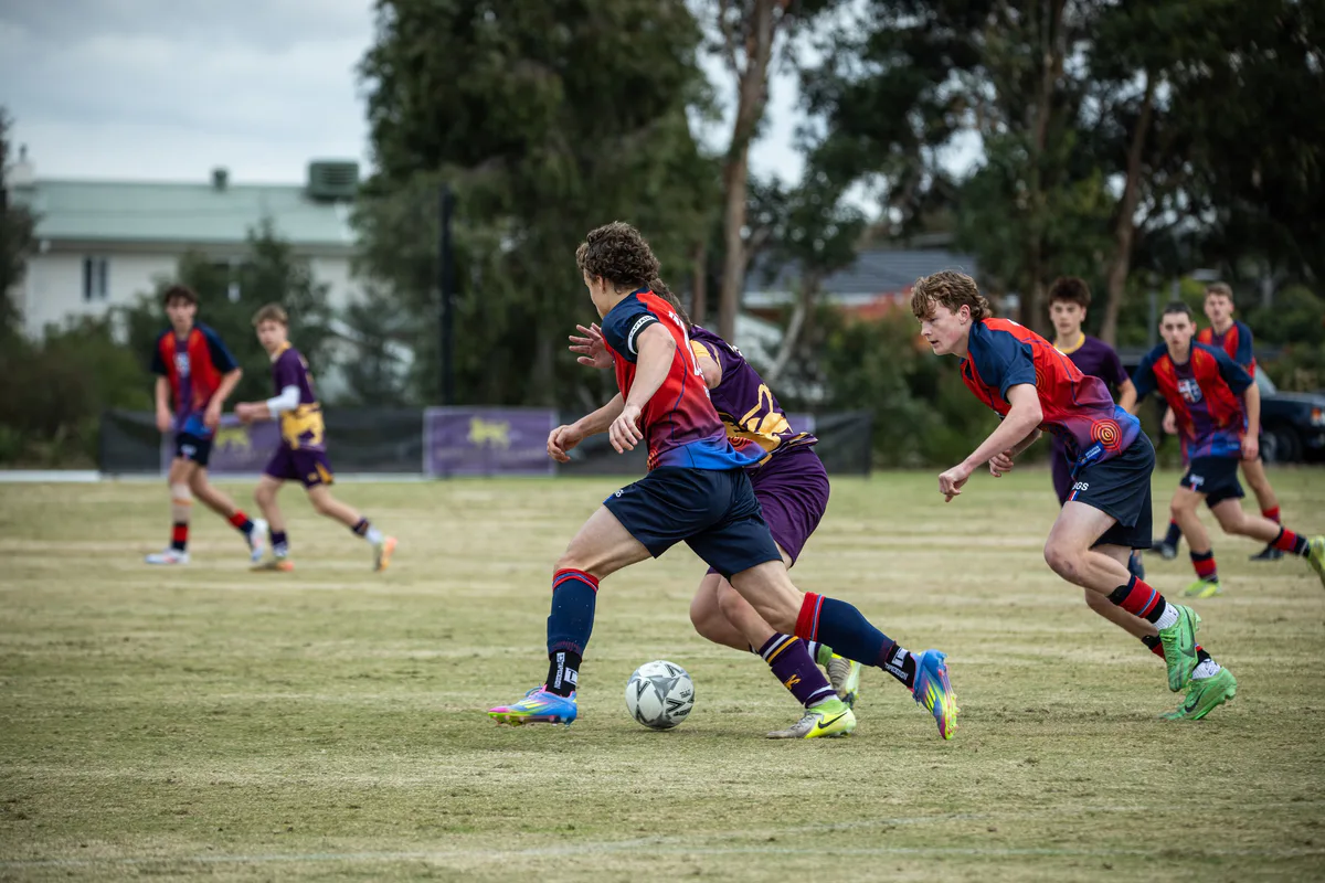 Brighton Grammar First XI players chasing the ball in a soccer match