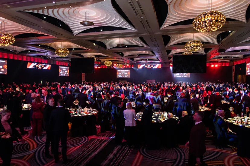 Guests filling the ballroom at round tables under chandeliers
