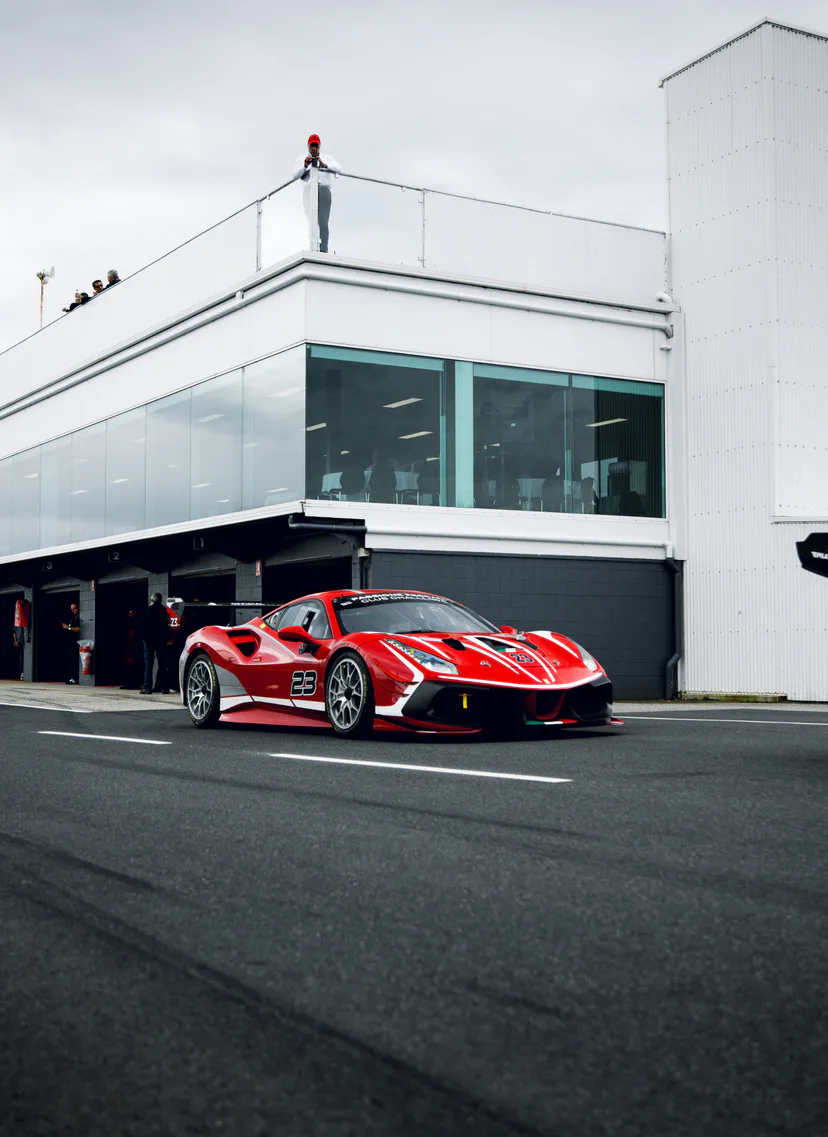 The red number 23 Ferrari Challenge car parked in pit lane outside the garages