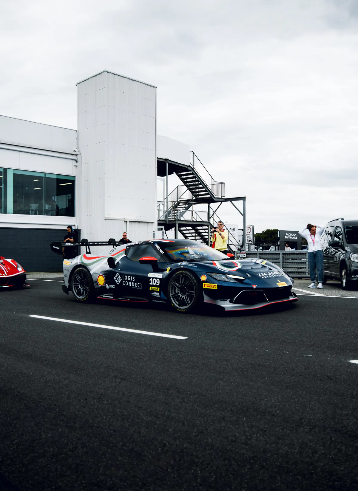 A dark blue Ferrari Challenge car rolls down pit lane.
