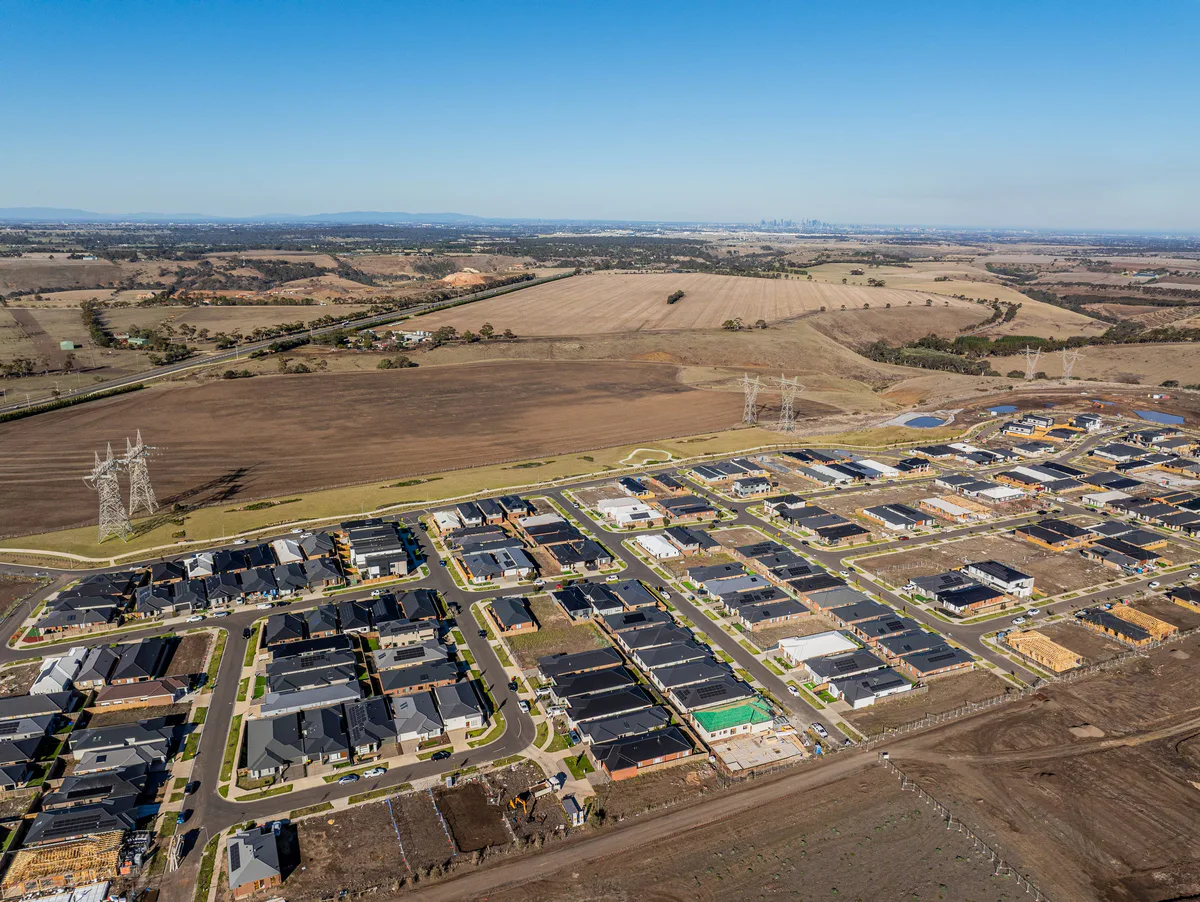 Drone view of a new estate on the city fringe, open paddocks running to the horizon