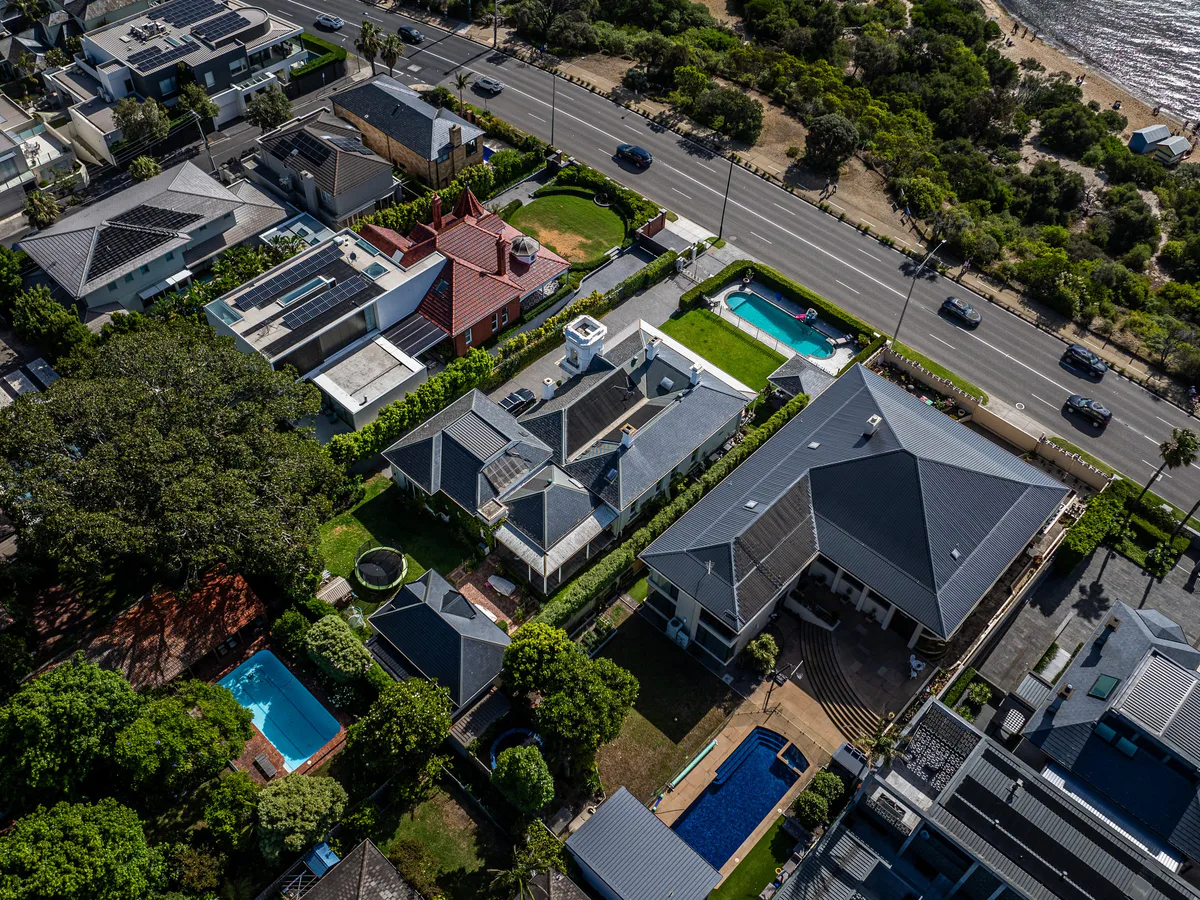 Aerial over homes with backyard pools on a leafy street