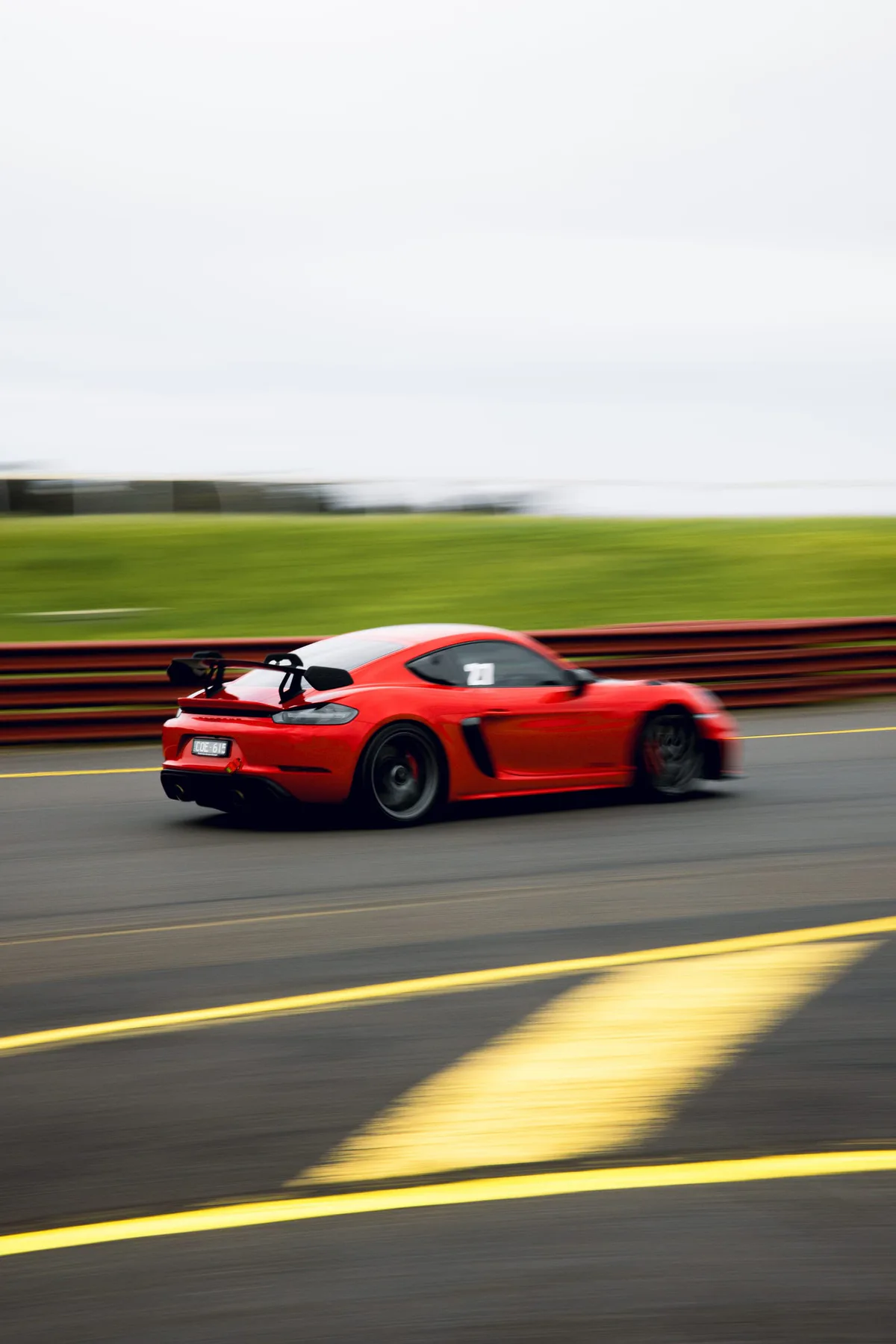 A red Porsche past the kerb, panned.