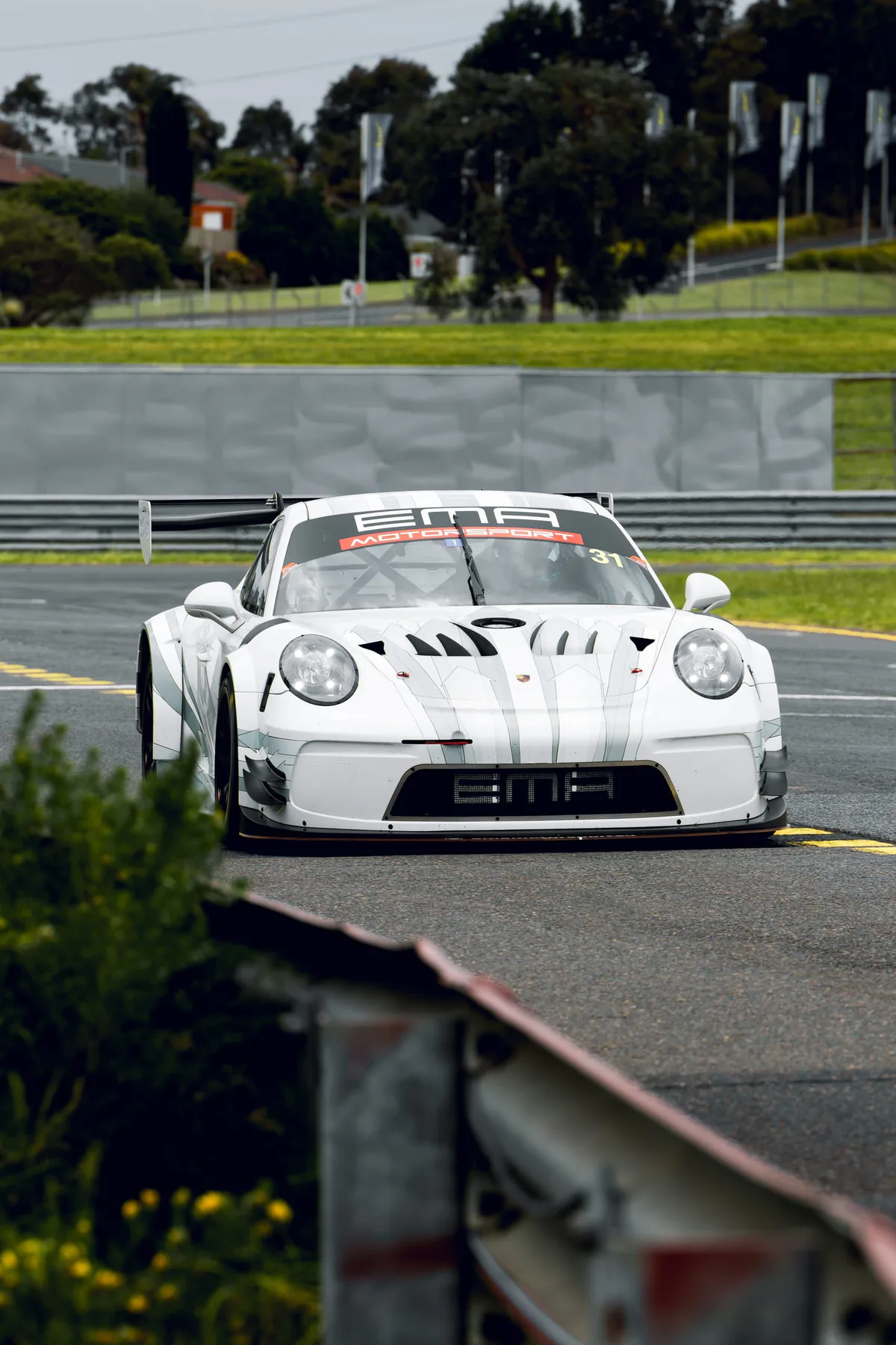 A white 911 GT3 R in pit lane, seen head on.