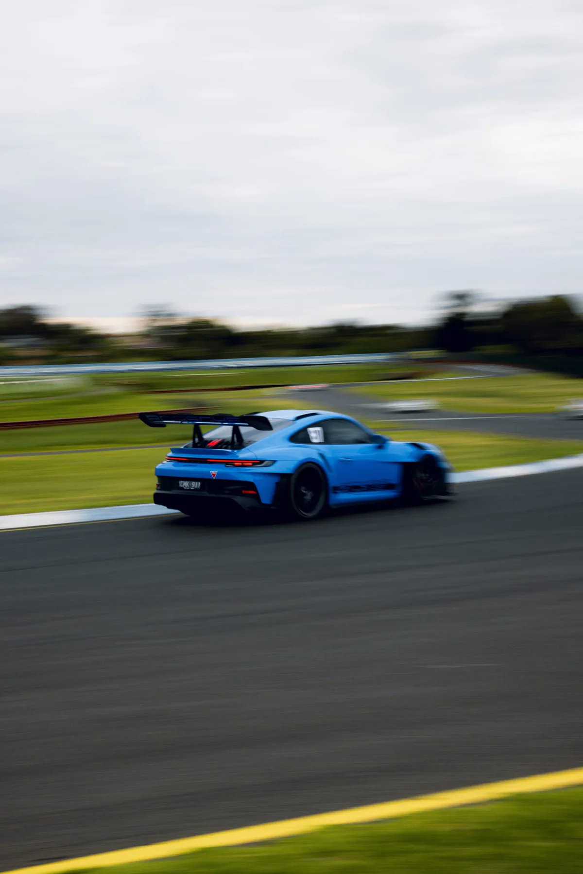 A blue GT car with a rear wing on the track.
