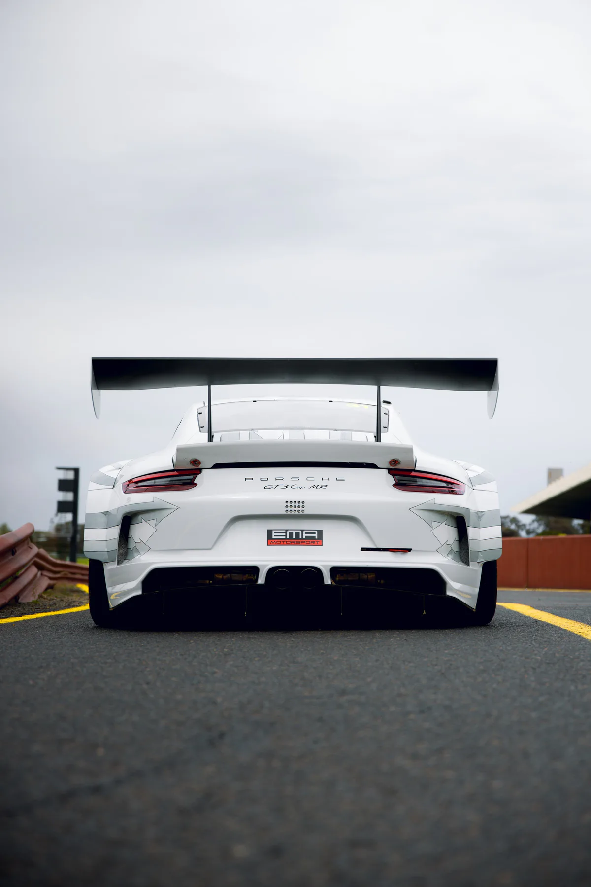 Rear of a white Porsche 911 GT3 Cup race car on pit lane, rear wing up