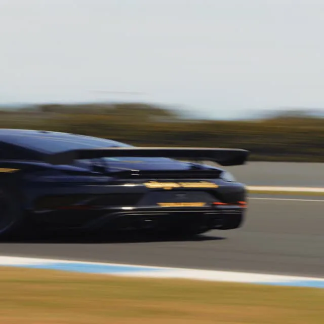A dark Porsche blurred at speed on the track at Phillip Island
