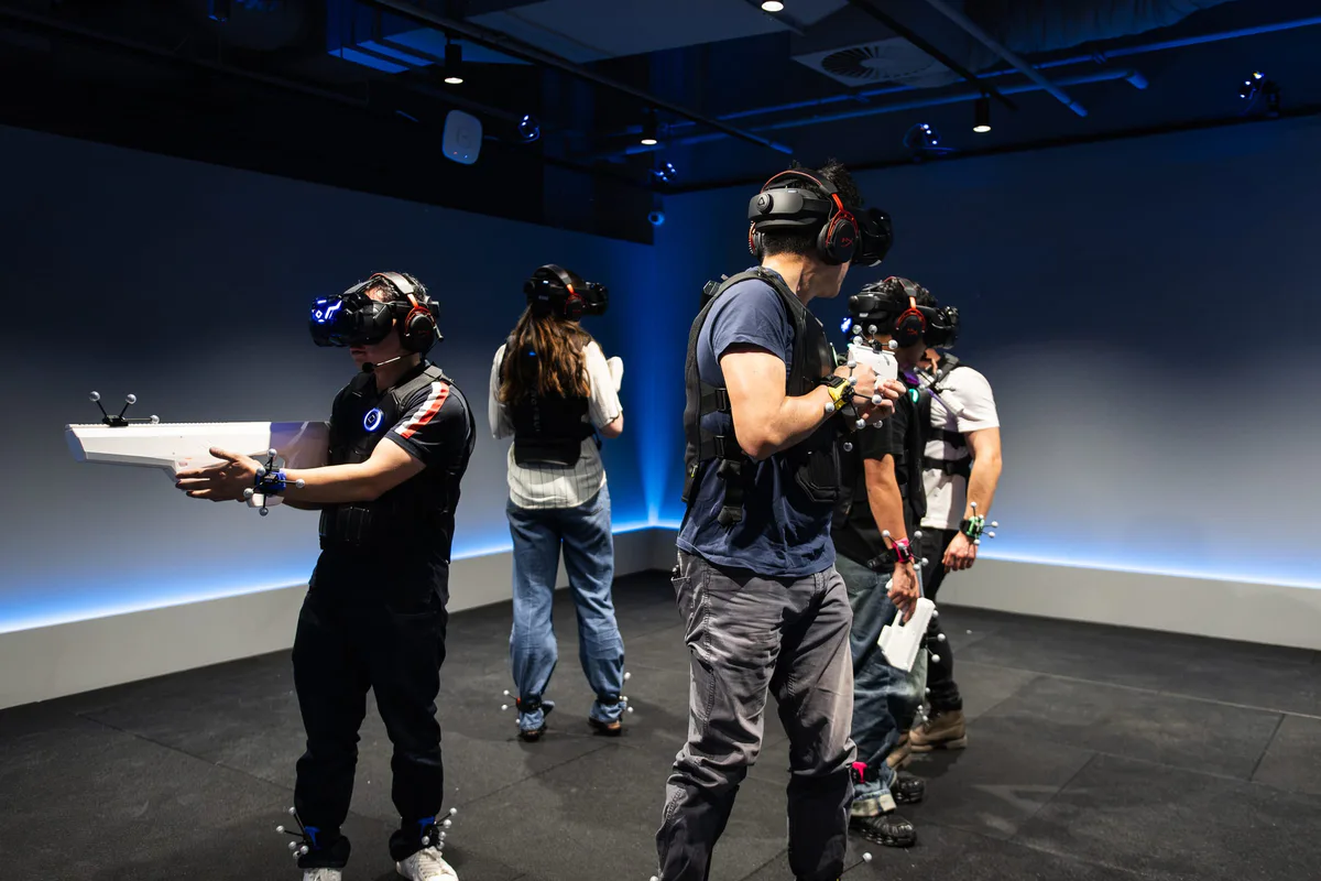 A group of players in headsets moving through a blue-lit game room