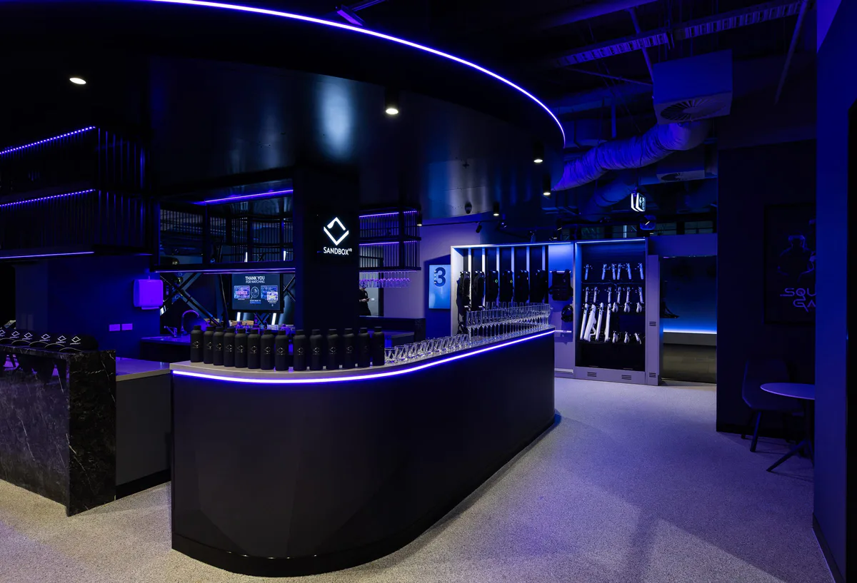 The bar counter under a ring of light, the Sandbox VR mark behind