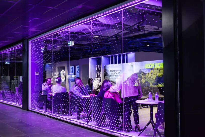 A glass-walled room lit purple, guests inside