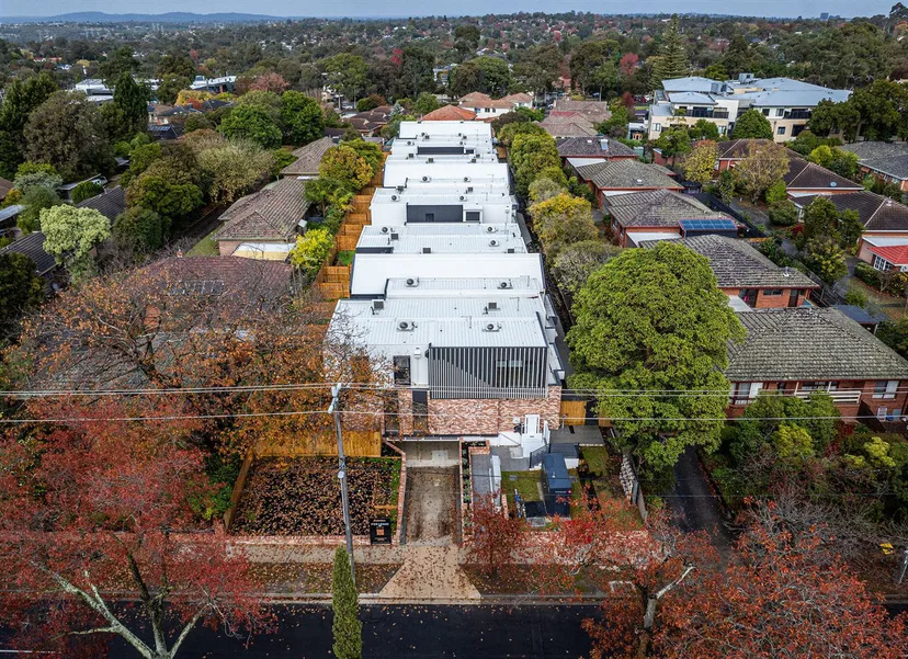 Drone view of a townhouse development among trees and neighbouring homes