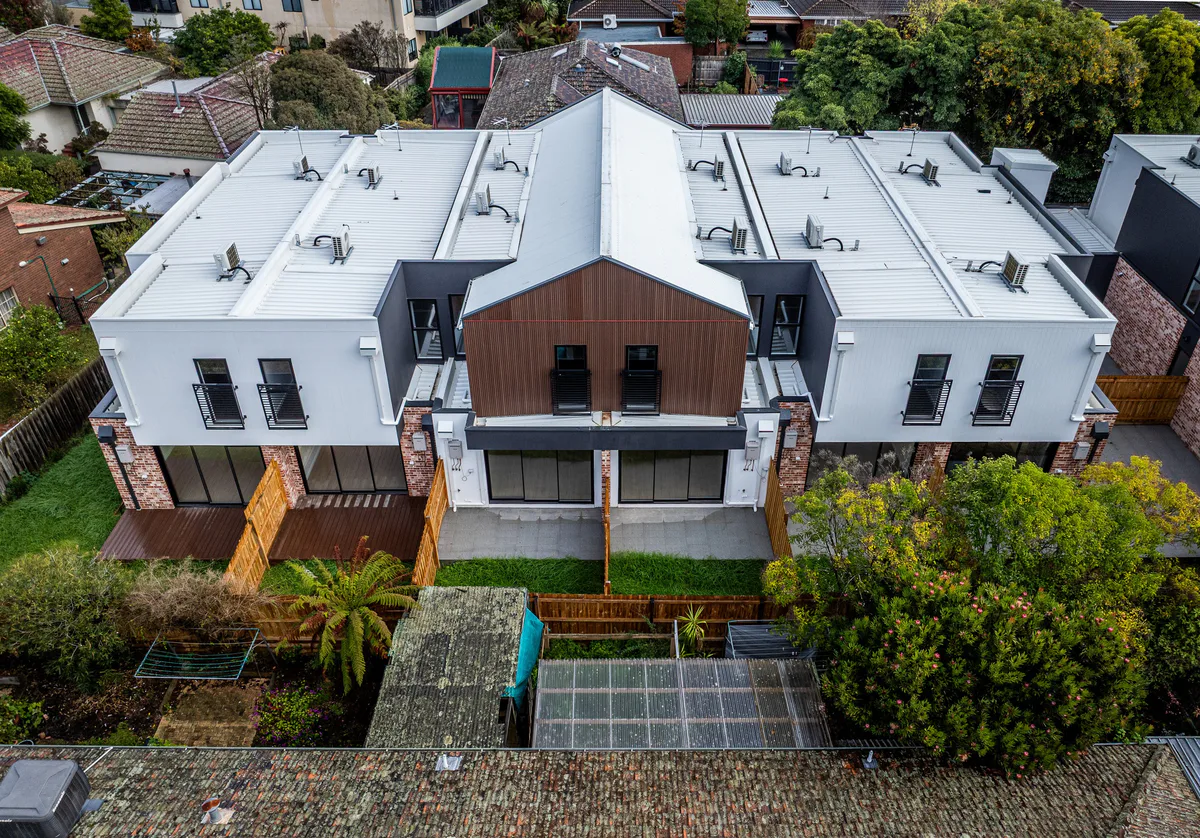 Drone view of a new double-storey townhouse block among mature trees