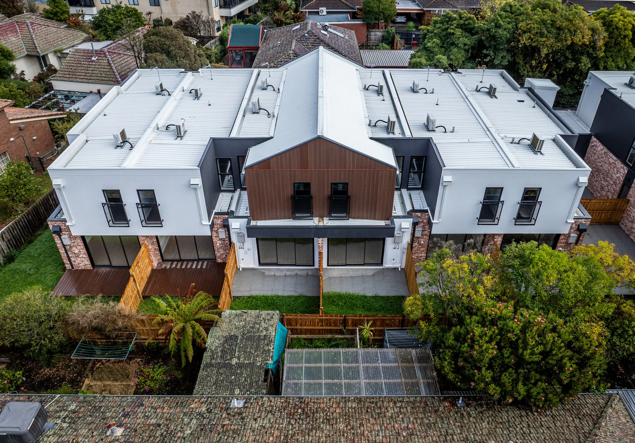 Drone view of a new double-storey townhouse block among mature trees