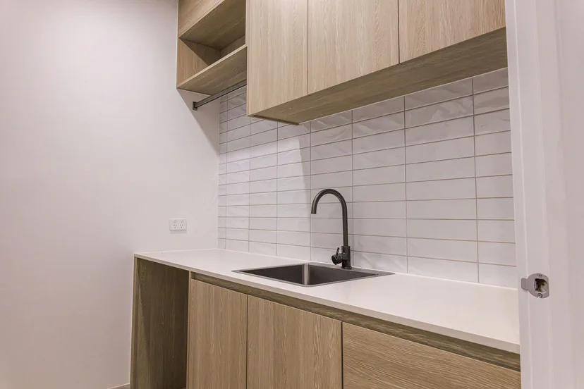 Kitchenette in a new home, timber cabinets, white tiles and a black tap