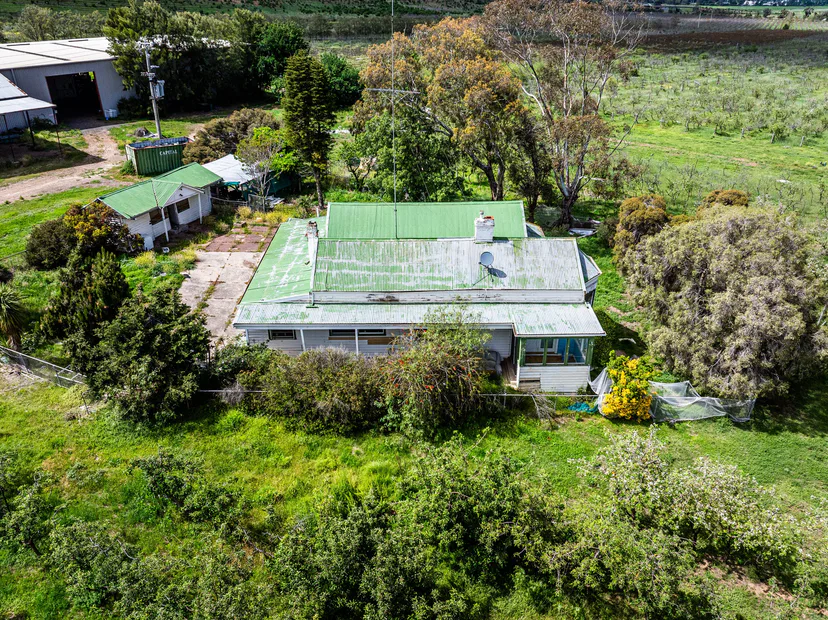 Drone view of a farmhouse with a green roof, sheds and gardens
