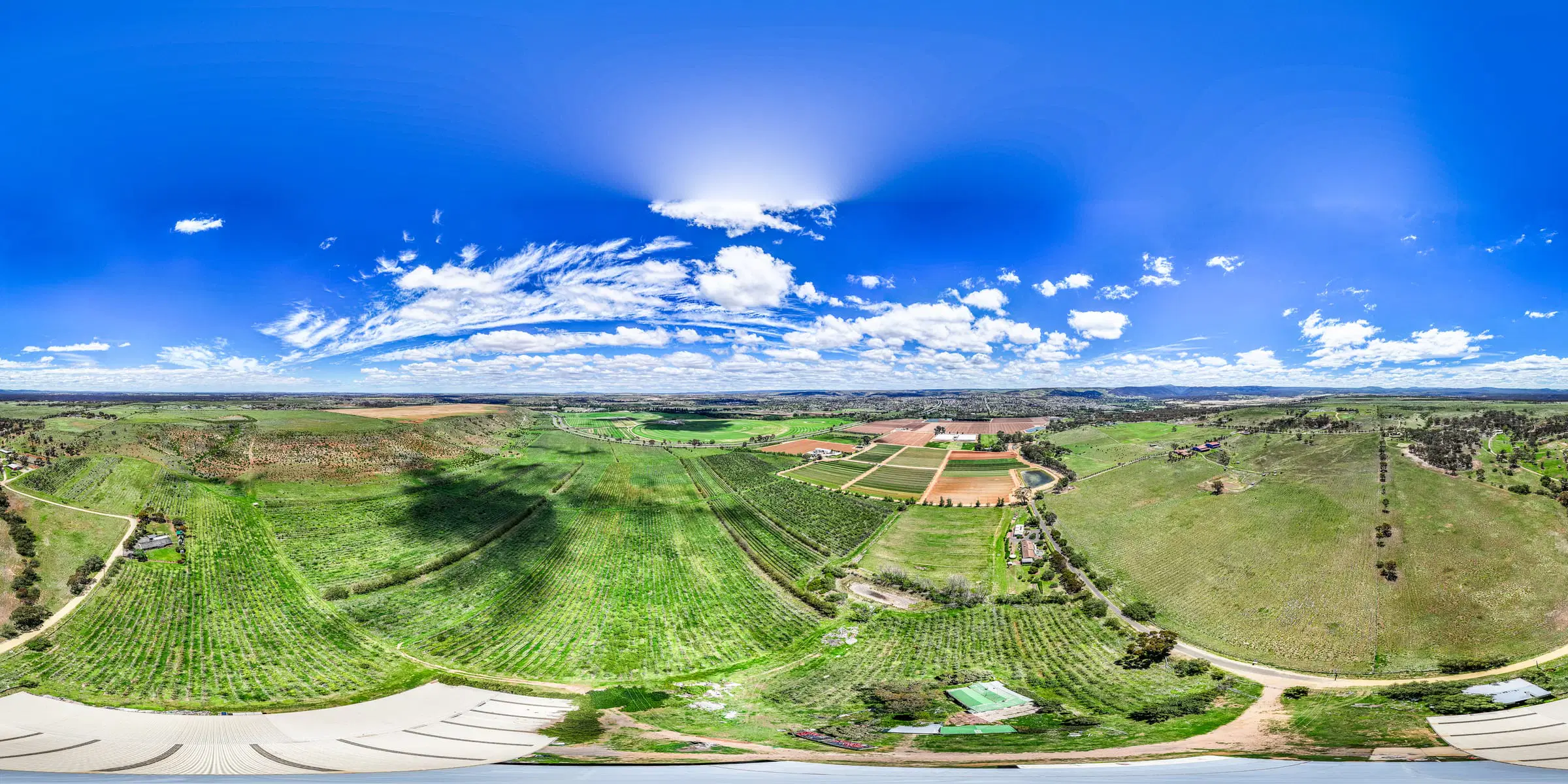 Wide aerial panorama of green farmland under a big sky, shot for Spectrum Real Estate