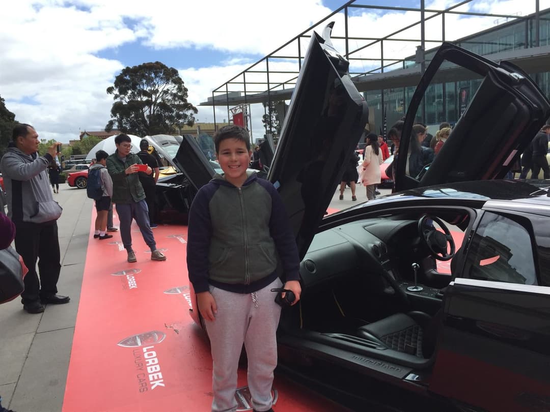 Gabe as a kid beside a Lamborghini at a Melbourne supercar show