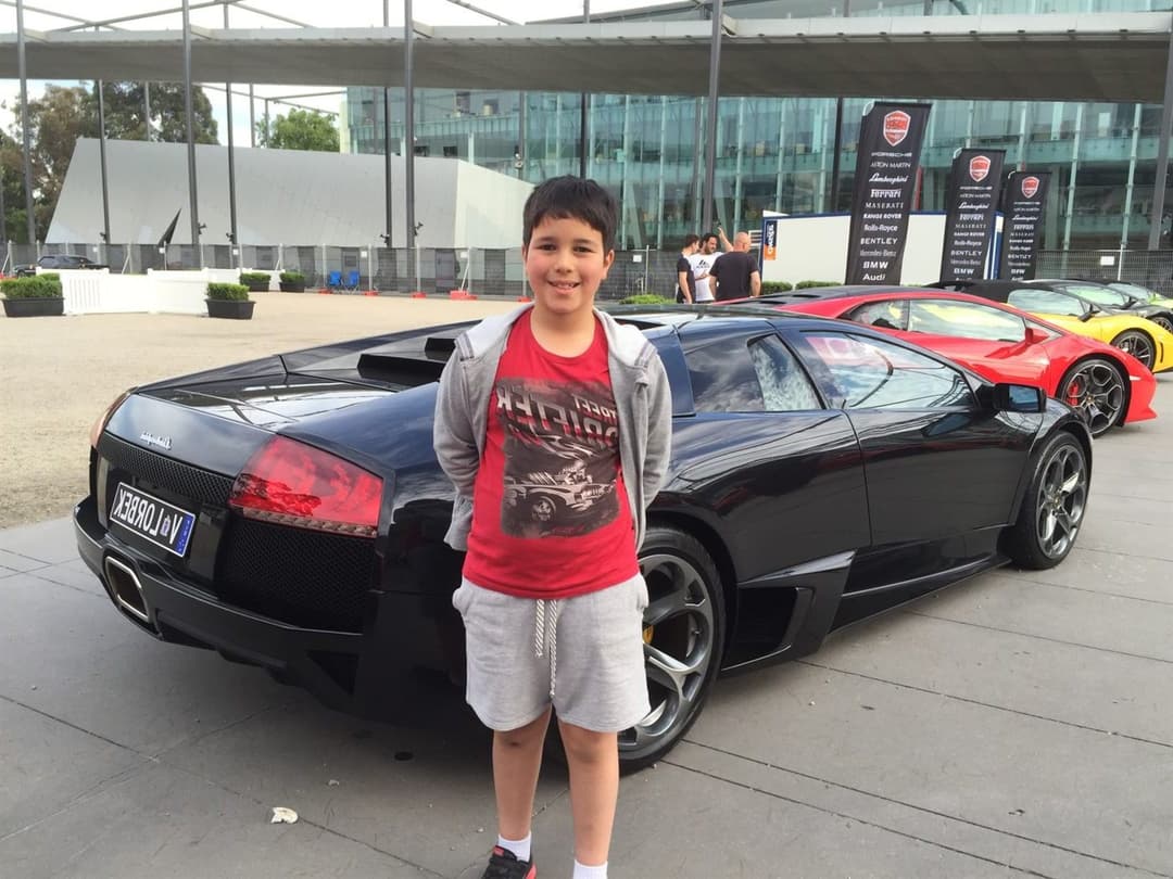 Young Gabe beside a black Lamborghini at a Lorbek car show
