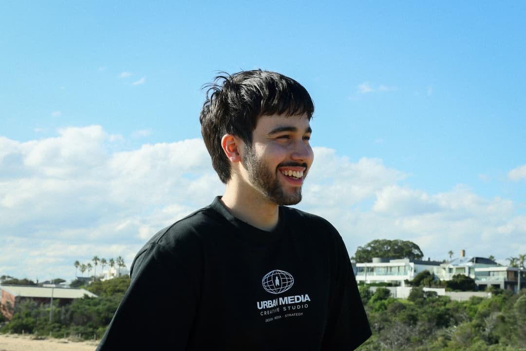 Gabe laughing on a beach with the Melbourne skyline behind him