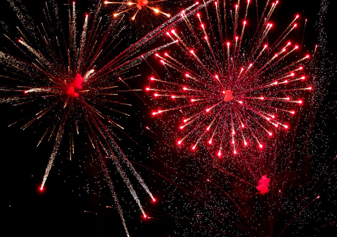 Red and gold fireworks bursting side by side against a black sky