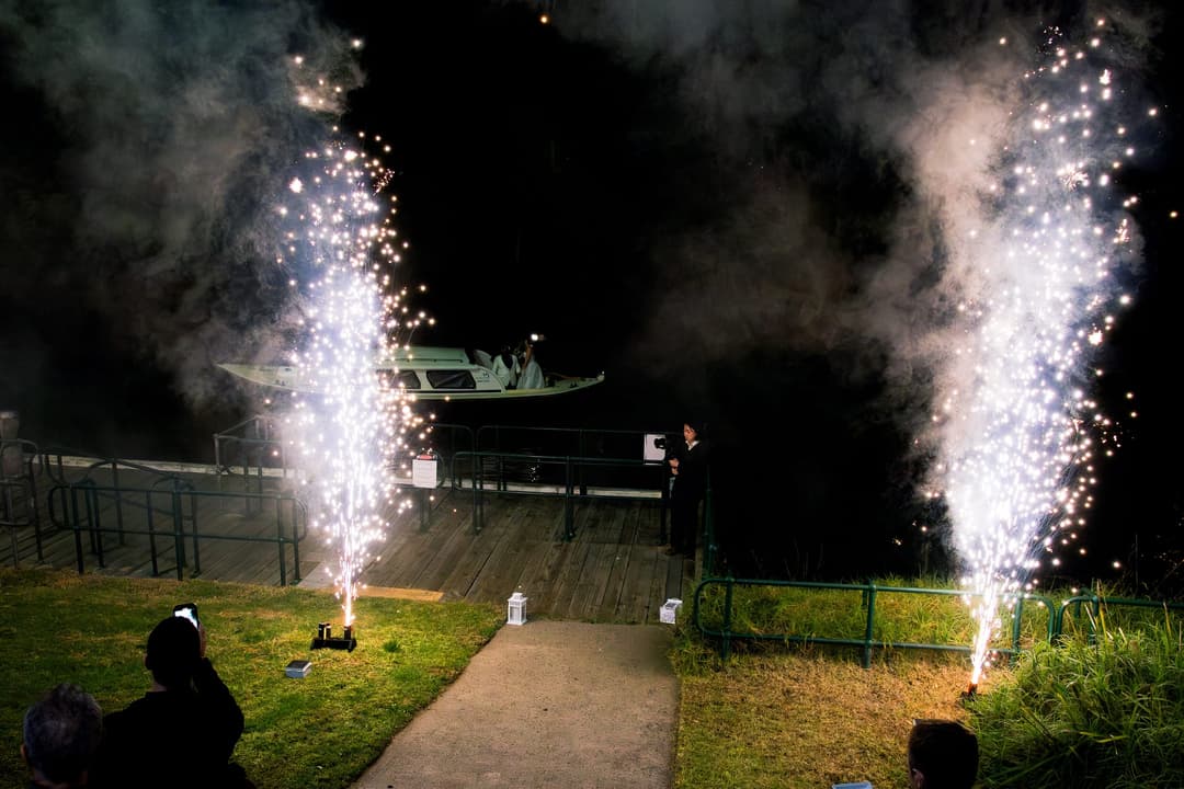 Ground fountains firing either side of a jetty at a waterside evening event