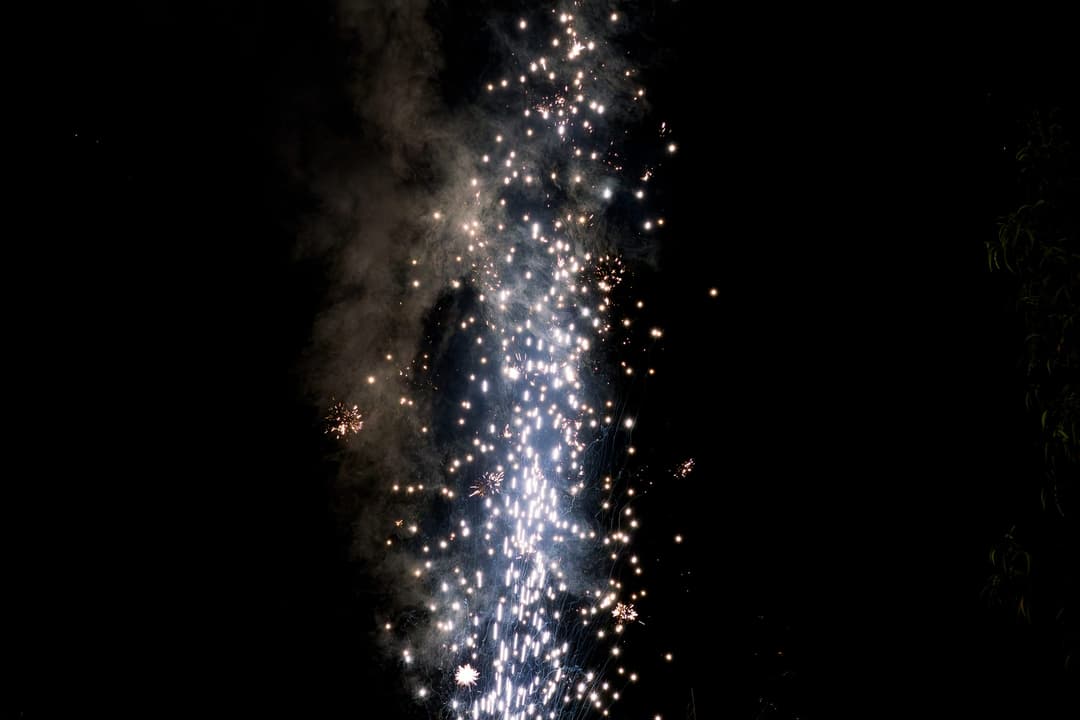 A cascade of white sparks falling through a column of smoke