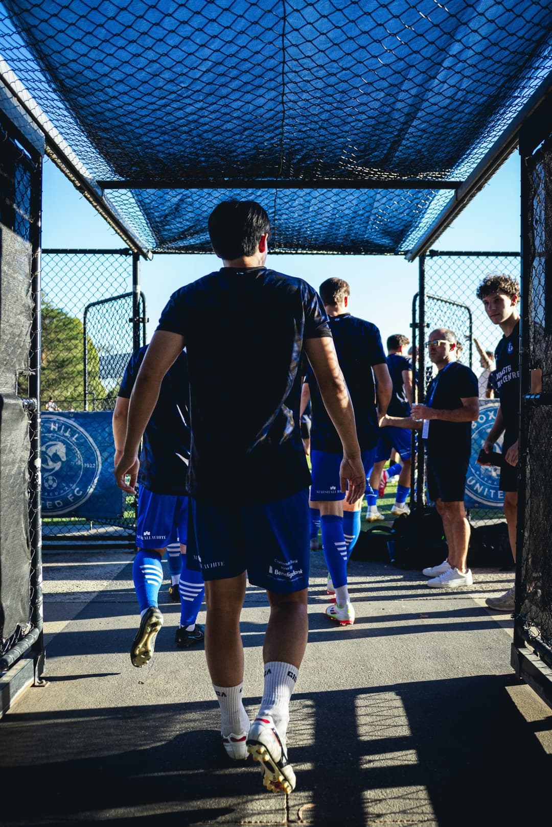 Players walking out through the caged tunnel to the pitch