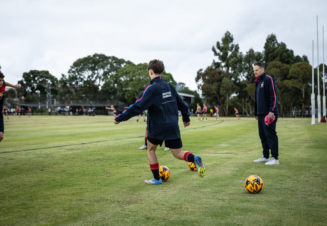 A Brighton Grammar student running a ball drill while a coach watches