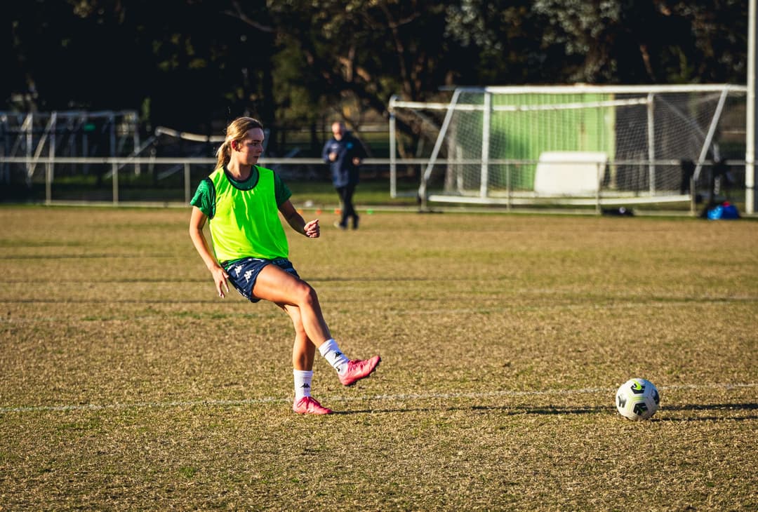 A Calder United player in a training bib passing the ball on a dry winter pitch
