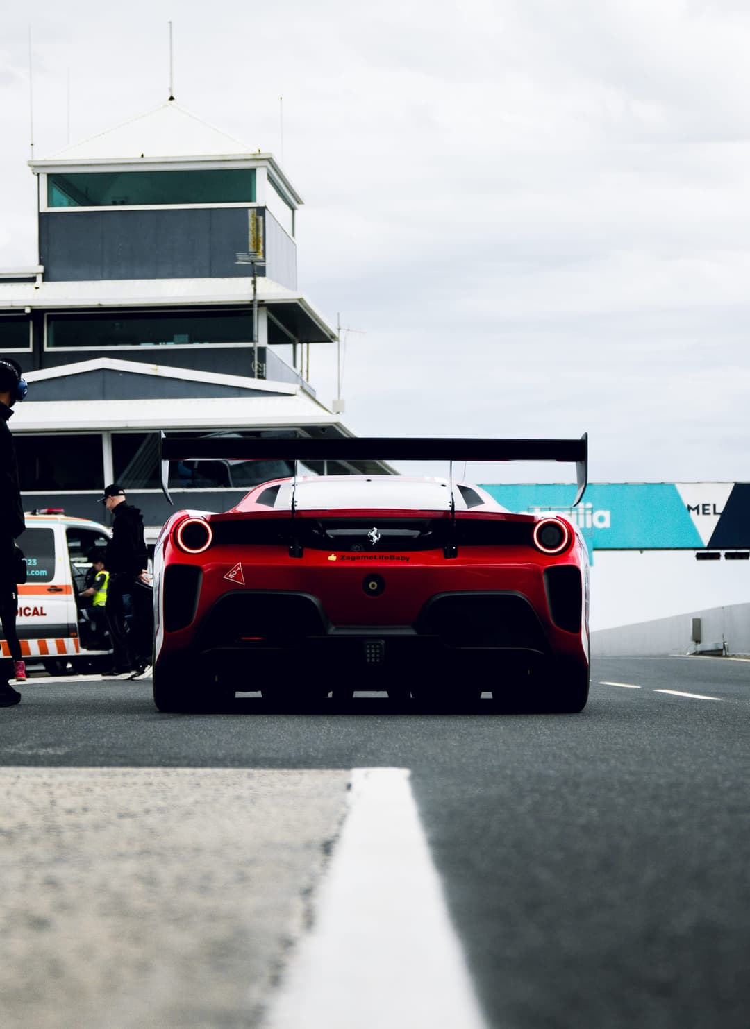Rear of the red number 23 Ferrari Challenge car heading out of pit lane