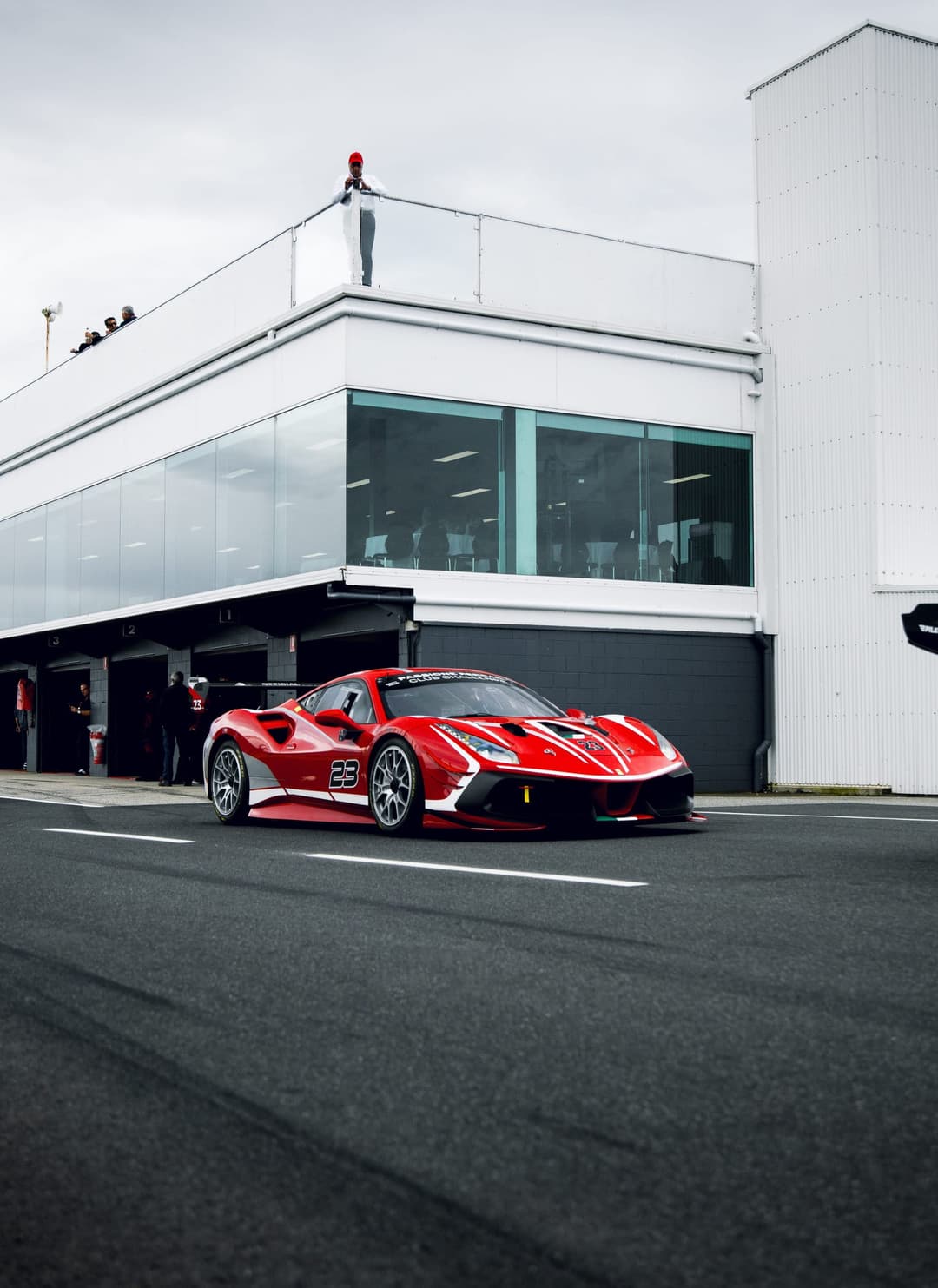 The red number 23 Ferrari Challenge car parked in pit lane outside the garages