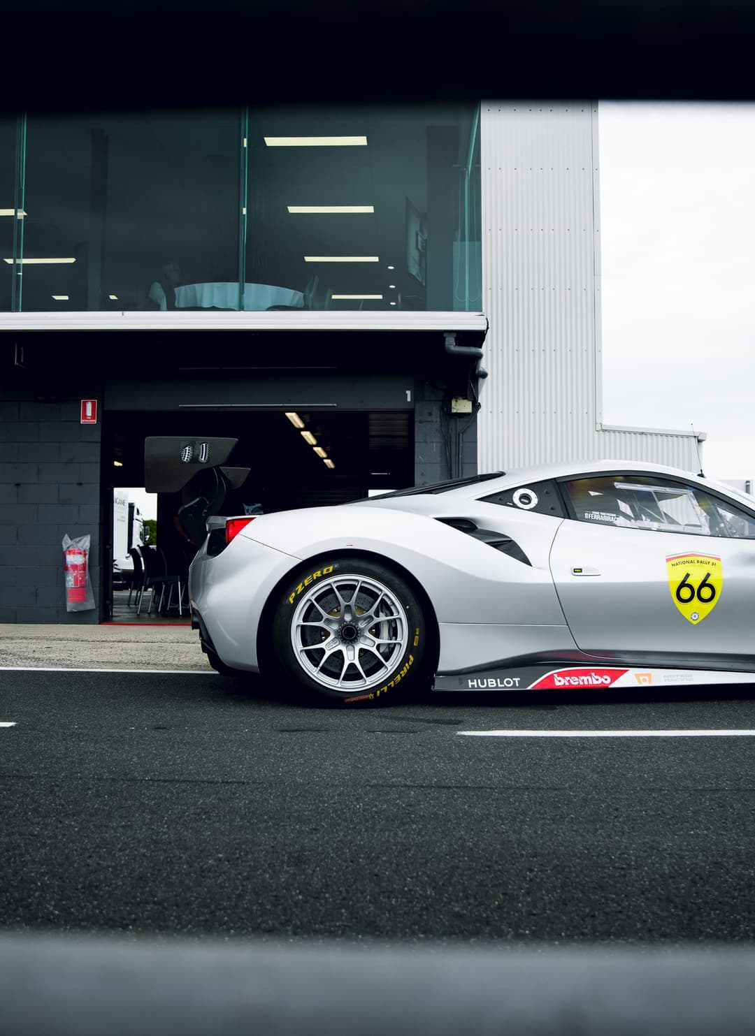 The silver number 66 Ferrari Challenge car in pit lane outside its garage
