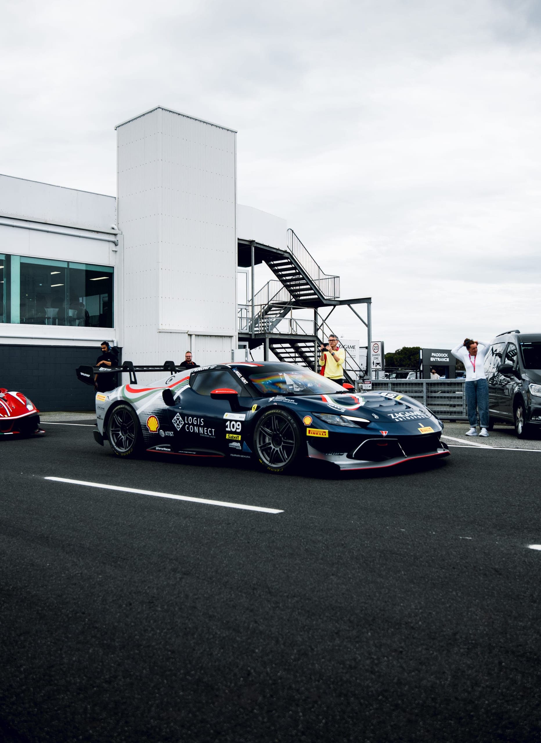 A dark blue number 109 Ferrari Challenge car in pit lane, crew watching