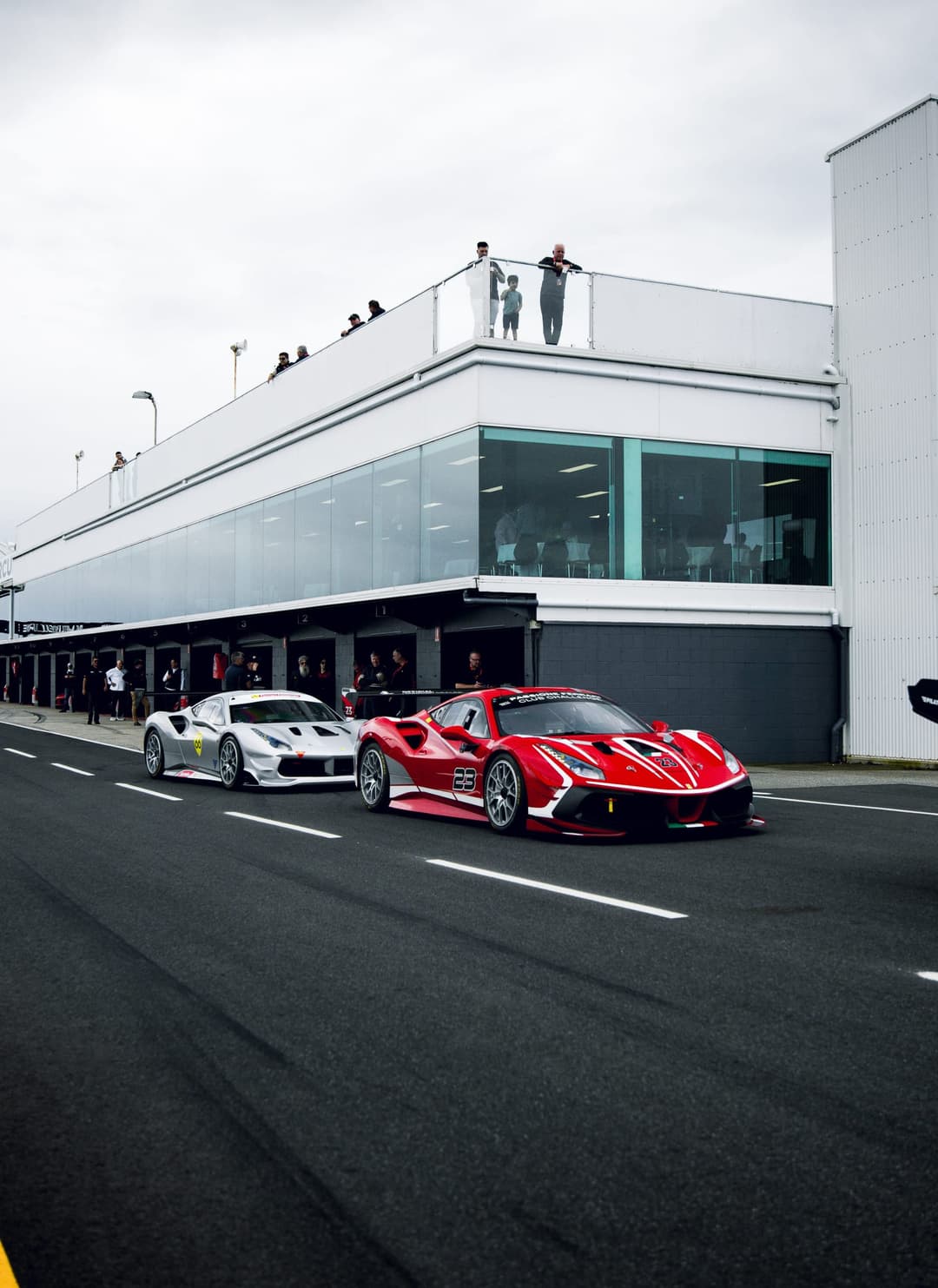 A red number 23 Ferrari Challenge car and a silver number 66 car in pit lane