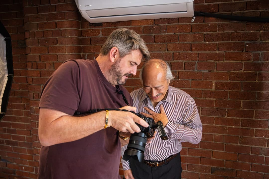 A photographer and a client looking at the back of the camera together. Frame 1 of 6. Open it