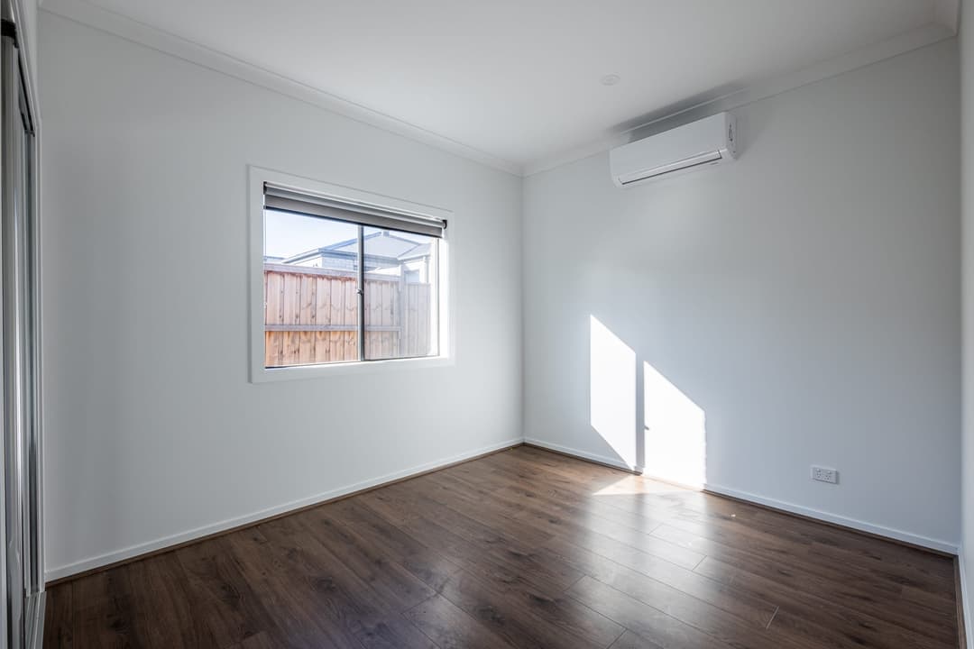 An empty bedroom in a new home, window onto the back fence