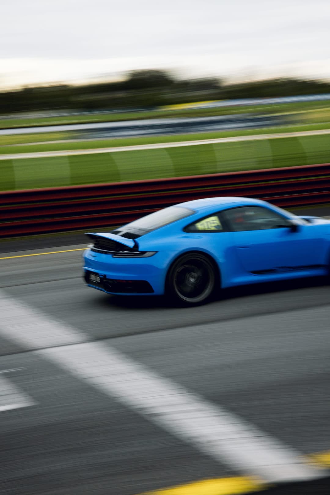 A blue Porsche 911 panned at speed past the kerbing