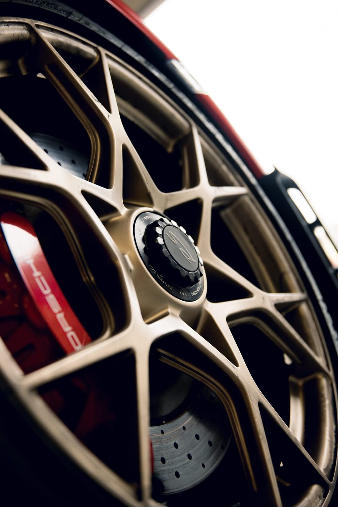 Close on a bronze centre-lock Porsche wheel and red brake caliper. Frame 1 of 6. Open it