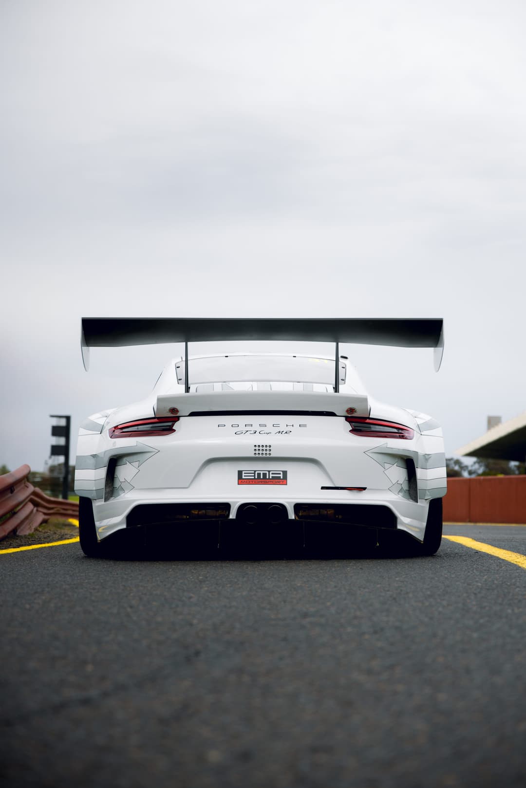 Rear of a white Porsche 911 GT3 Cup race car on pit lane, rear wing up